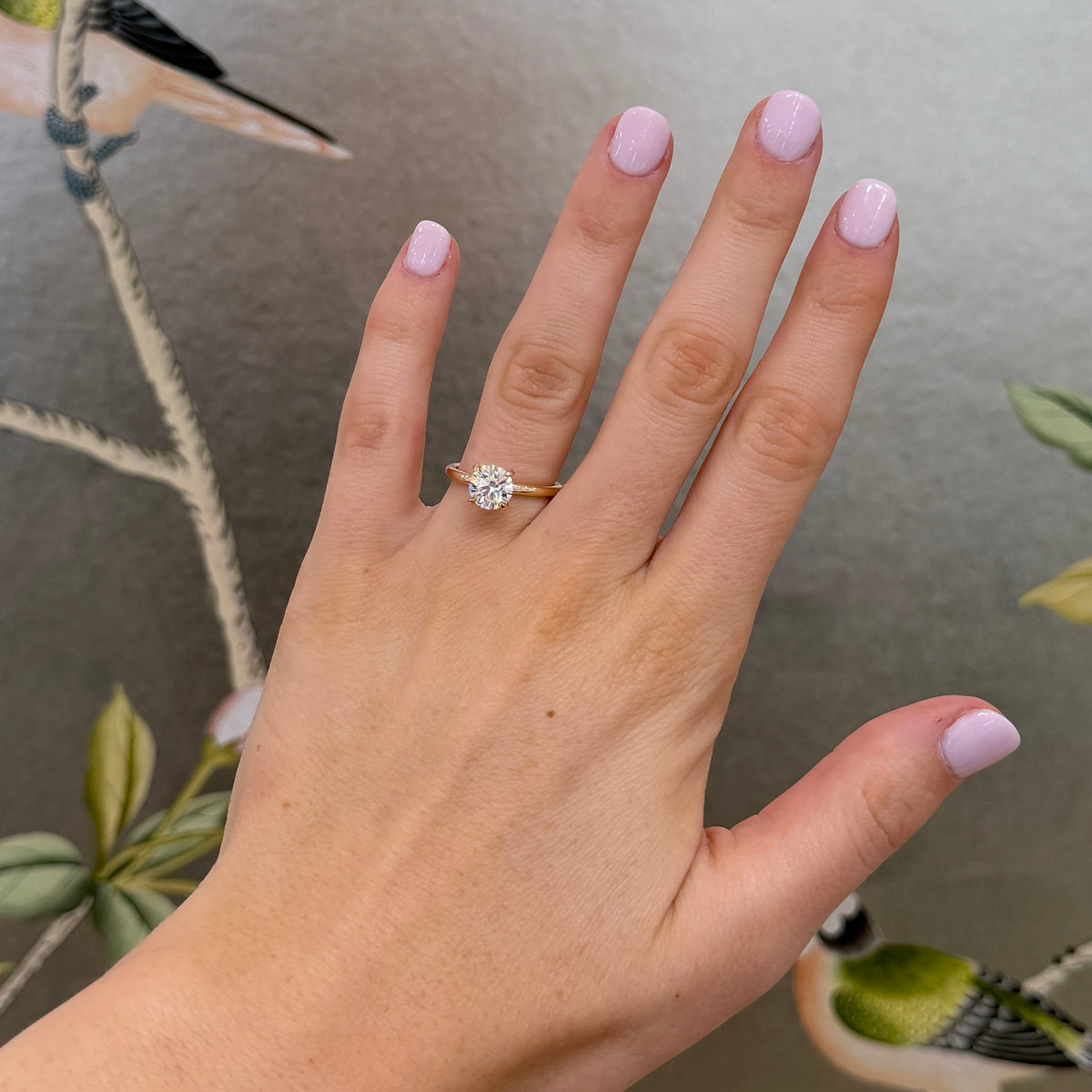 1.5ct round diamond solitaire engagement ring with a 14K yellow gold band worn on a hand.