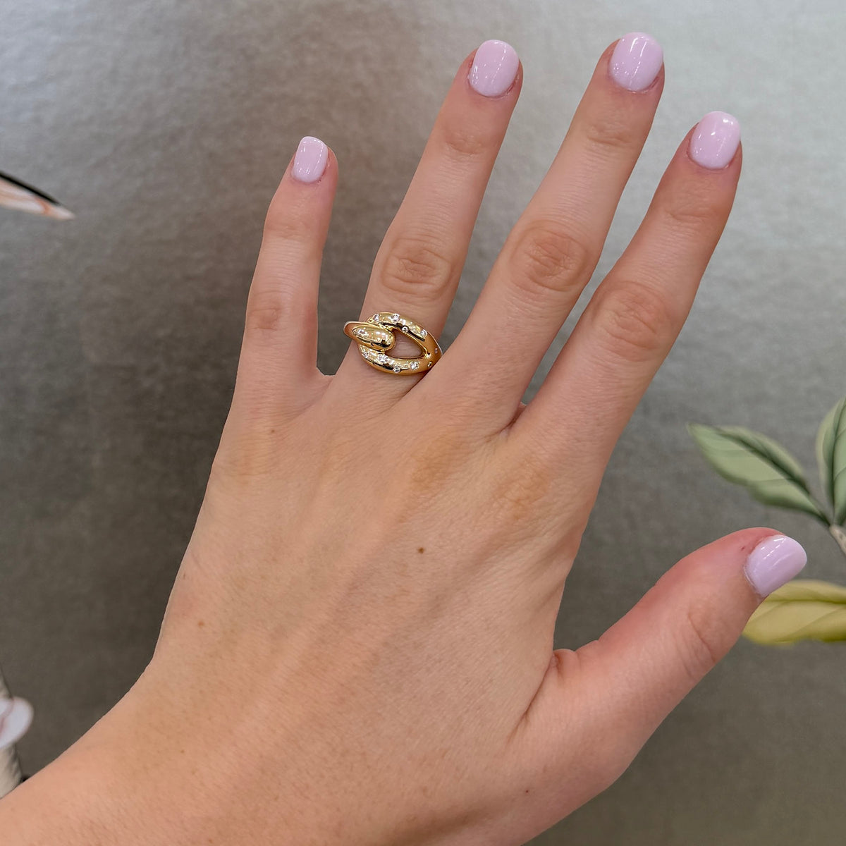 Diamond 18K yellow gold pouf buckle ring worn on the ring finger, showing its size and fit.