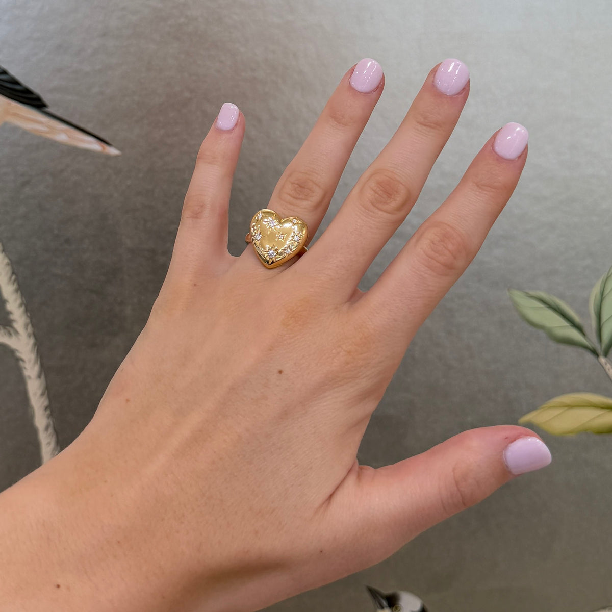 Diamond starburst 18K yellow gold pouf heart ring worn on the ring finger, showing its size and fit.