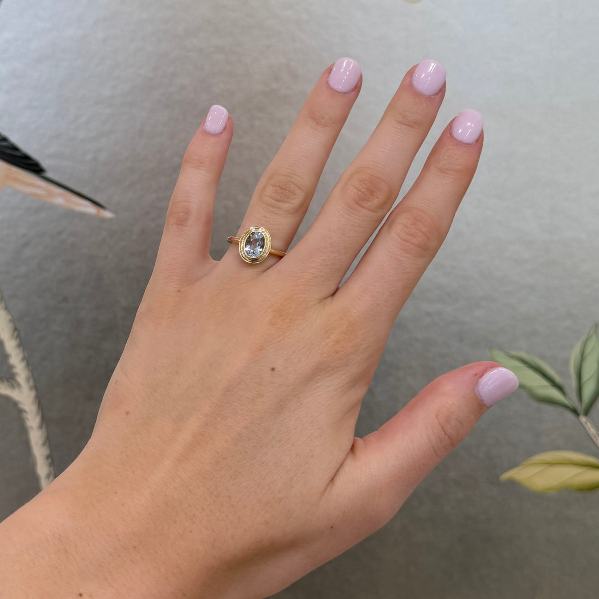 Model hand wearing Aquamarine 14K Yellow Gold Double Bezel Ring.