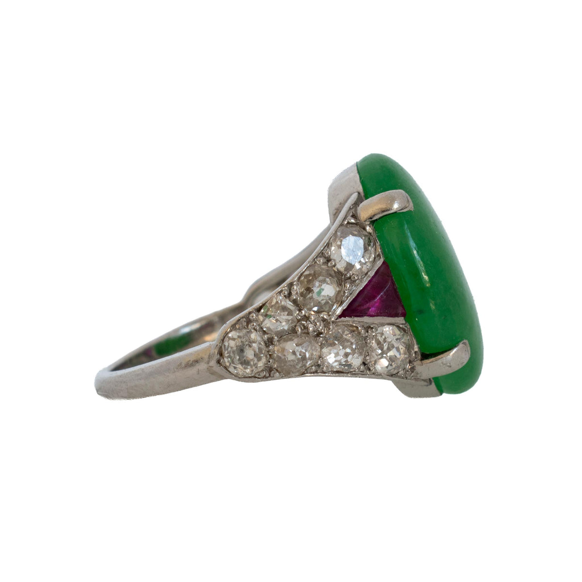 Side view of the jadeite platinum ring showing its raised cabochon, diamond-set shoulders and triangular ruby accent.
