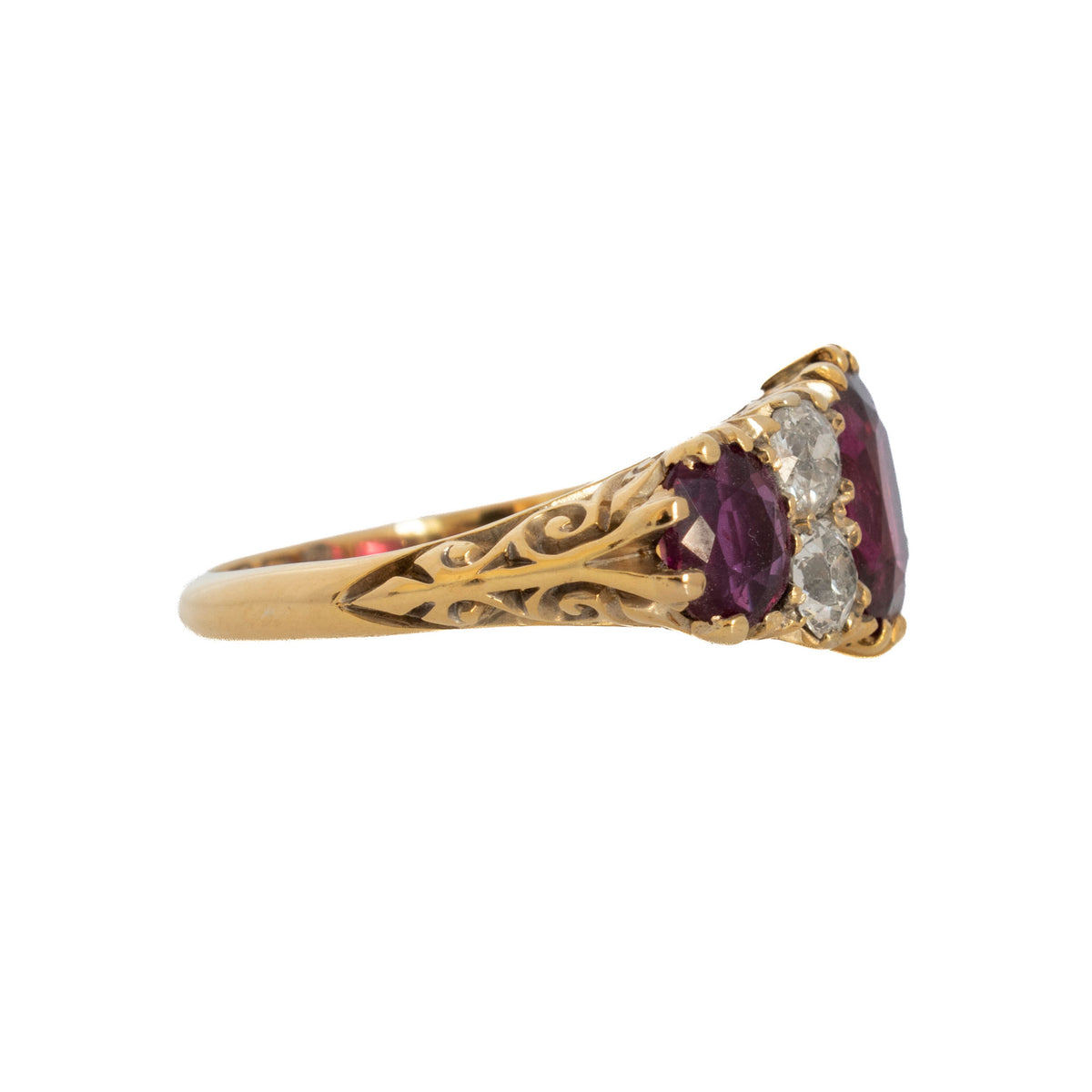 Side view of a Victorian-style ruby and diamond ring showing ornate scrollwork on the 18K yellow gold band.