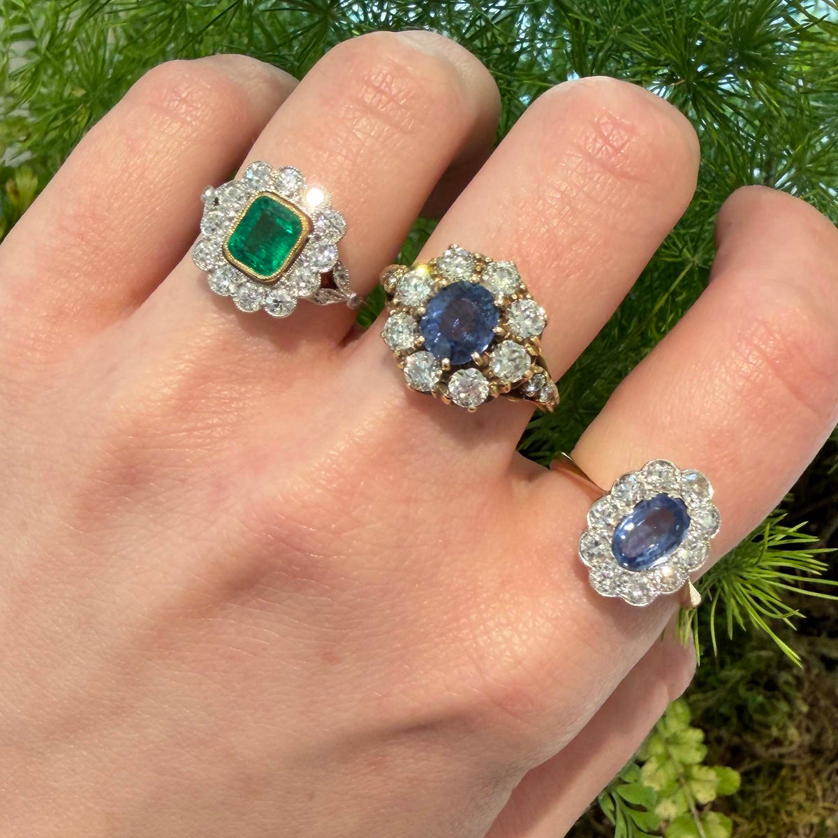 Edwardian sapphire and diamond gold ring worn on a hand alongside two other gemstone cluster rings.