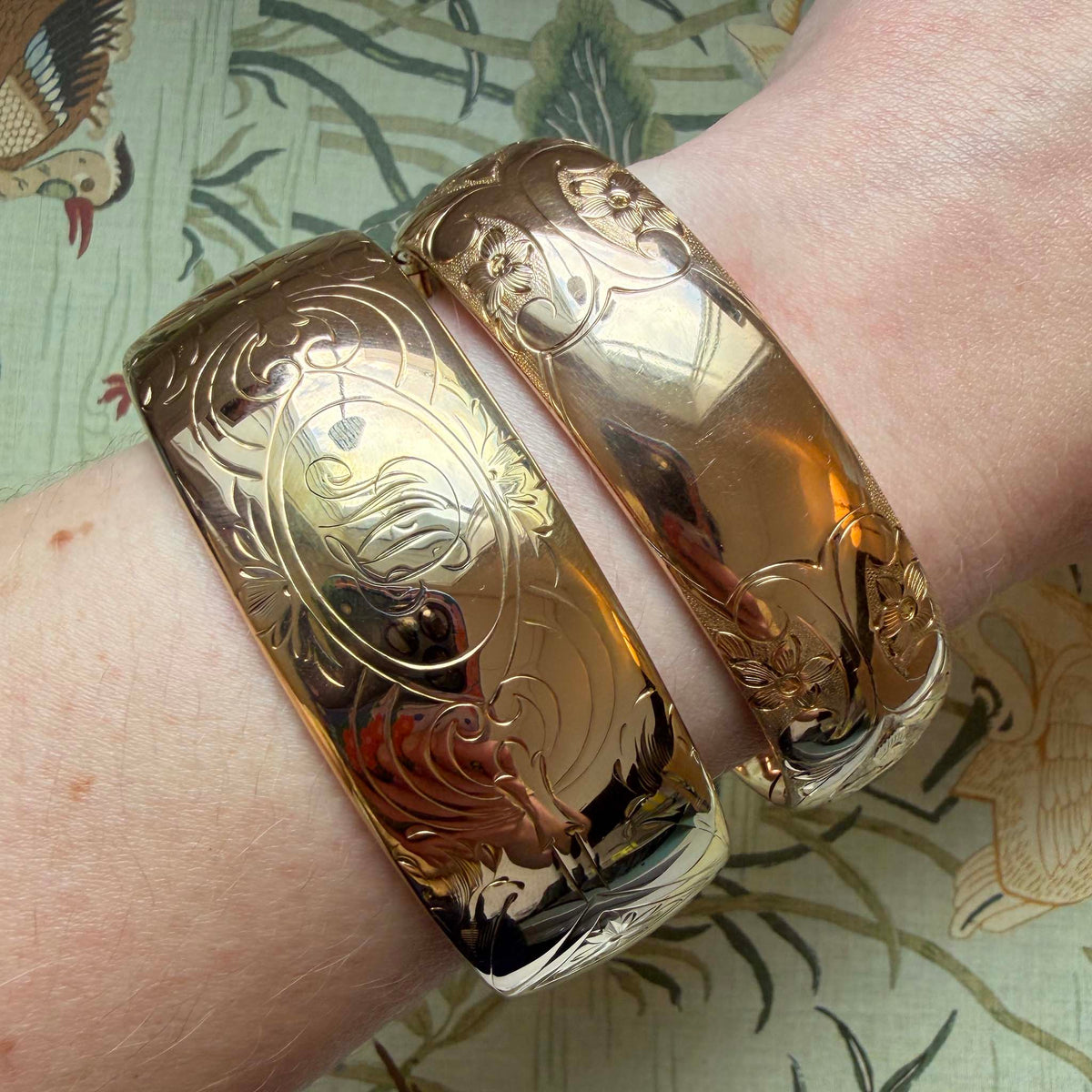 Vintage engraved wide gold-filled bangle worn on a wrist beside another engraved bangle.