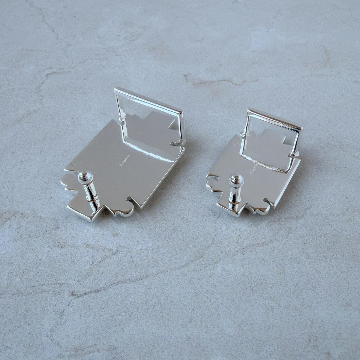 Back view of two sizes of silver-plated belt buckles, showing the fixed loops and fastening pins.