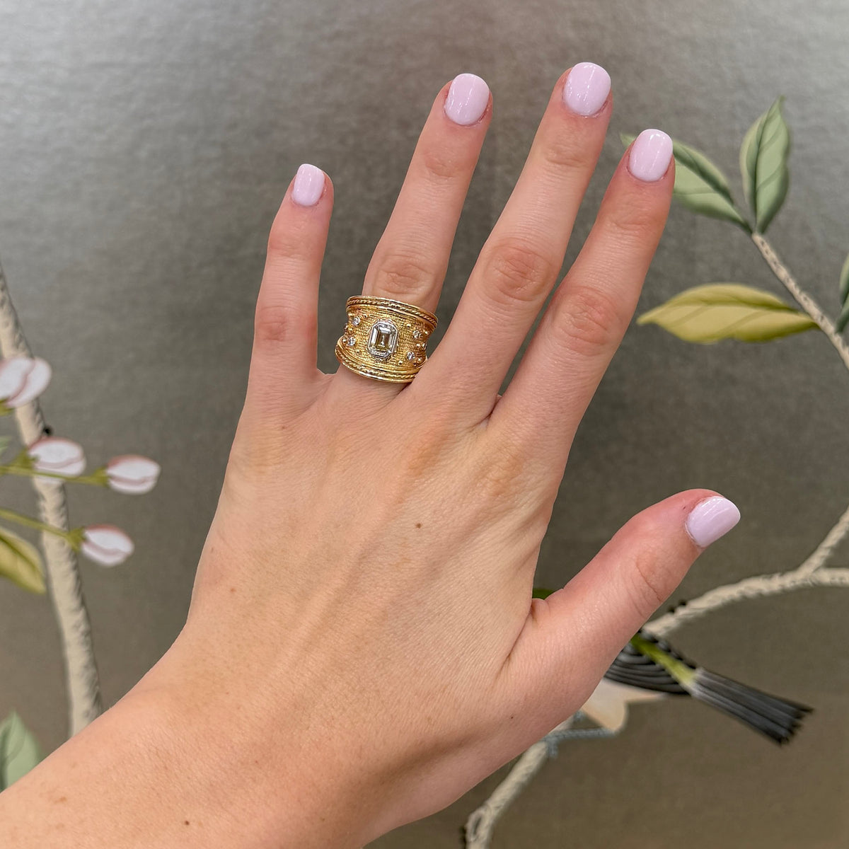 Emerald-cut diamond Byzantine-style ring in 14K yellow gold worn on a hand, showing the wide band's scale.
