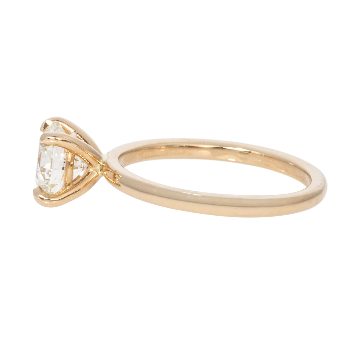Side view of a round diamond solitaire engagement ring showing the open four-prong setting and 14K yellow gold band.