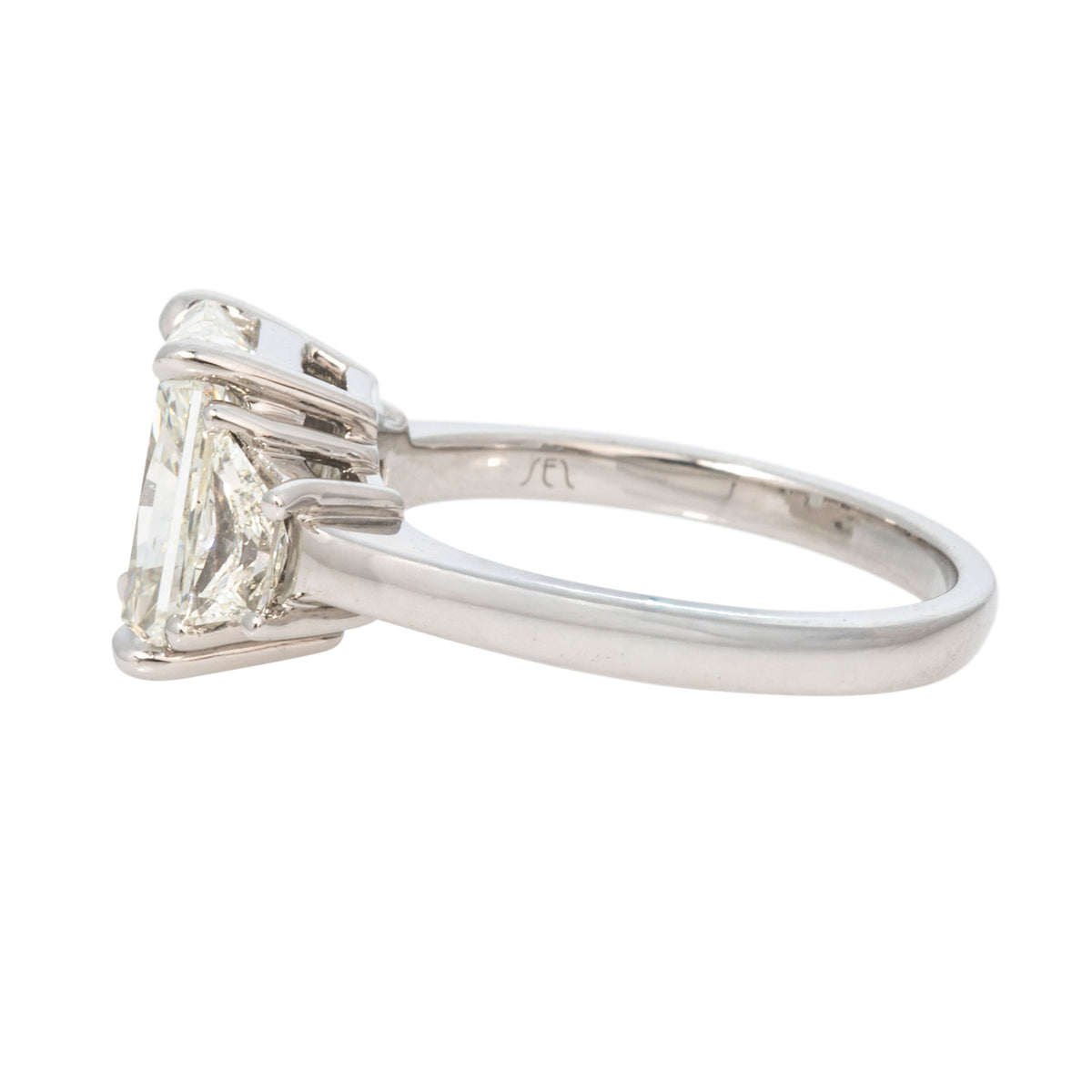 Side view of a platinum three-stone diamond ring showing the raised prong setting and polished band.