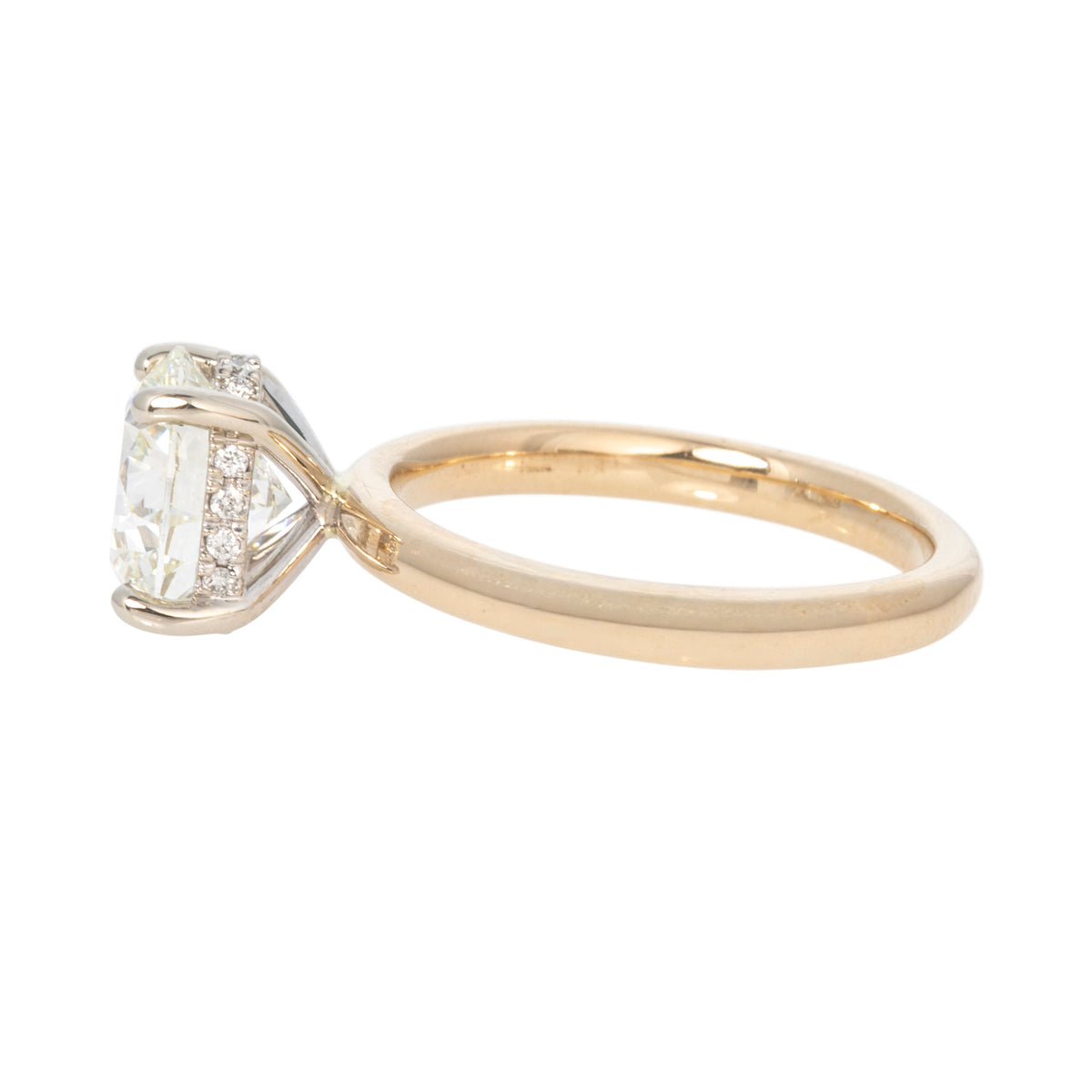 Angled side view of a round diamond solitaire engagement ring with a hidden halo and polished 14K yellow gold band.