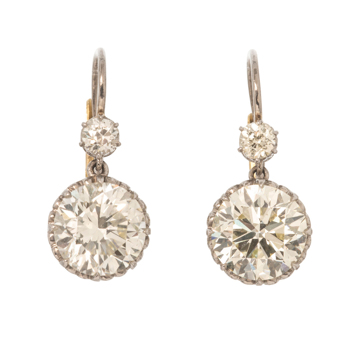 Victorian-style platinum double drop earrings with small Old Mine cut diamonds above larger round diamonds.