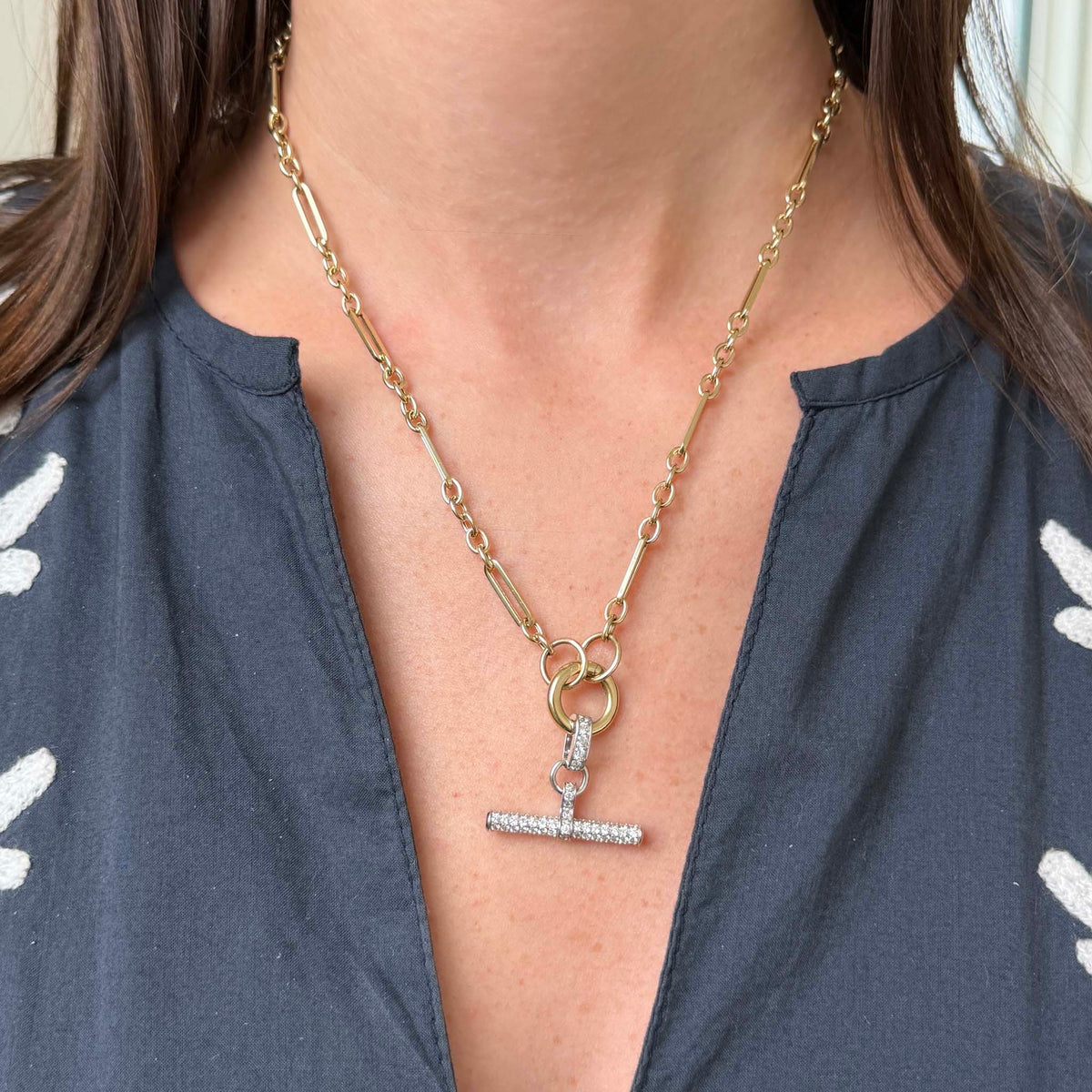 Model wearing a 14K yellow gold mixed link necklace with a diamond pavé white gold T-bar pendant centered on the chest.