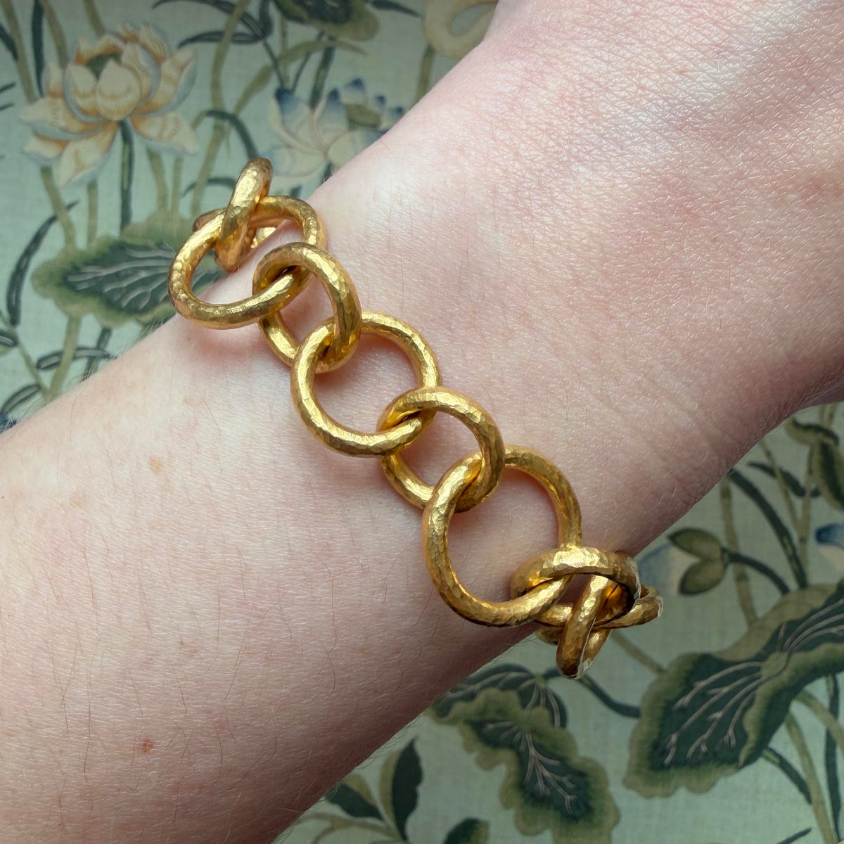 14K yellow gold bracelet worn on the wrist, showing mixed-size round links with a hammered finish.