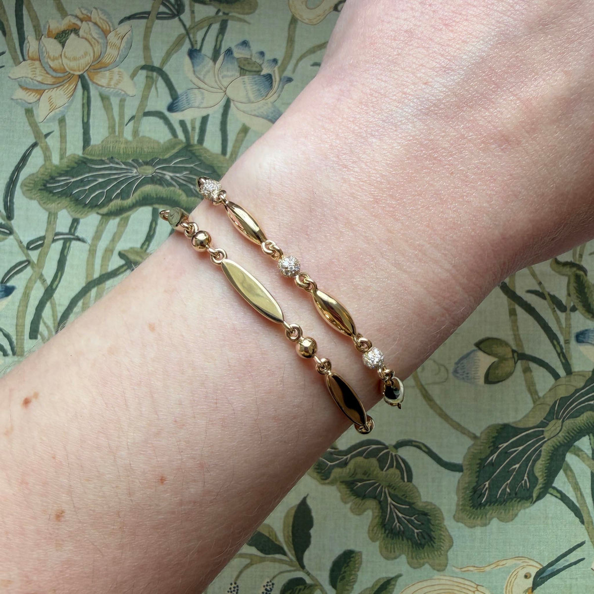 14K yellow gold rice bead bracelet with pavé diamond beads worn on the wrist beside the 14K yellow gold engravable rice bead bracelet.