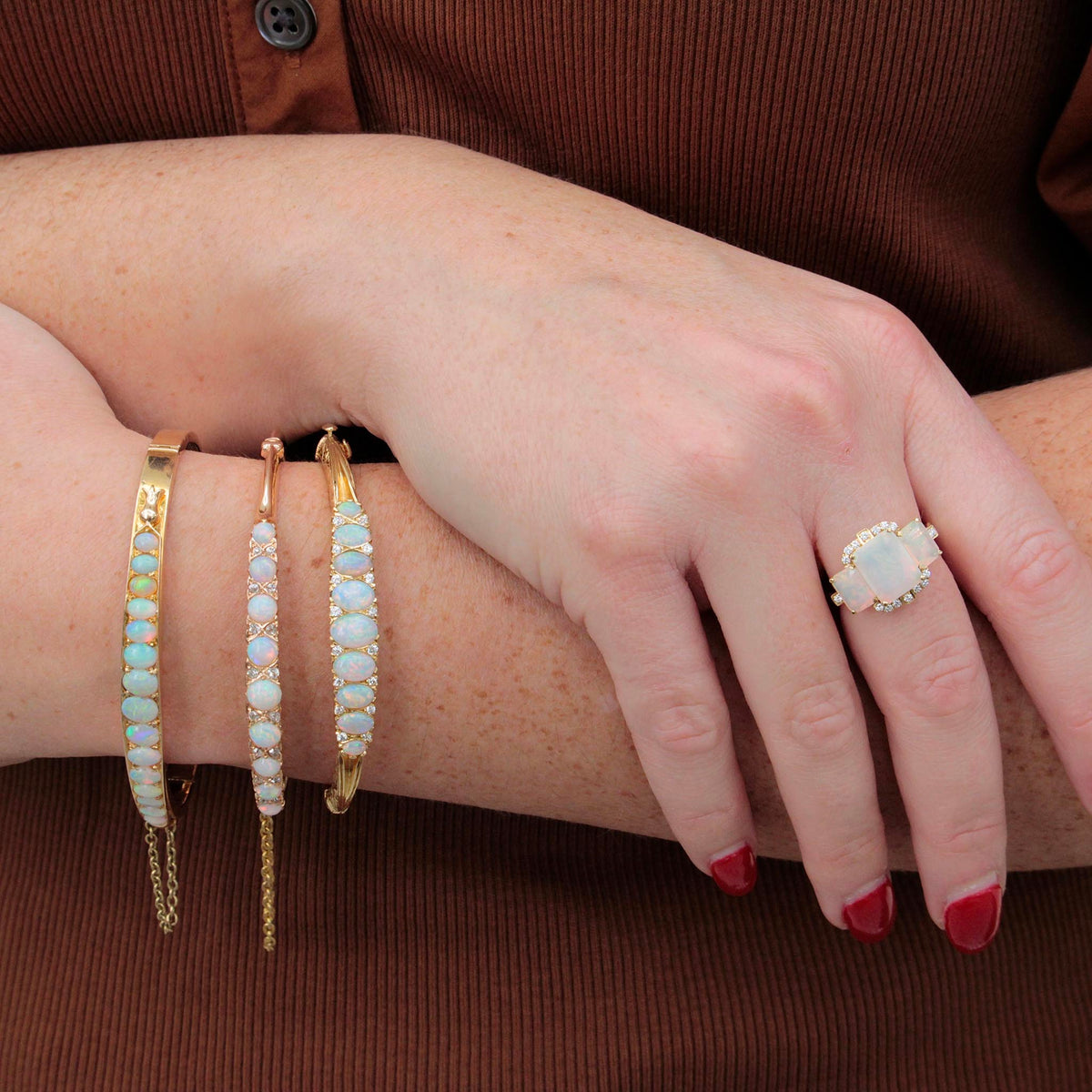 Goshwara three-stone opal and diamond ring worn on a hand, styled with three opal bracelets.⠋