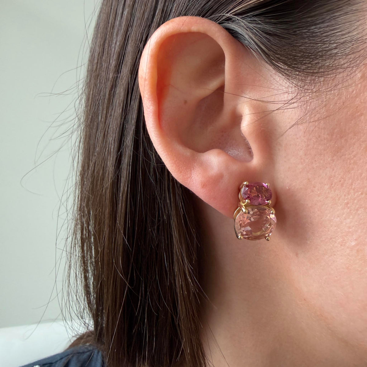 Pink tourmaline and morganite two-stone earring worn on the ear, showing the contrasting pink gemstones in 14K yellow gold.