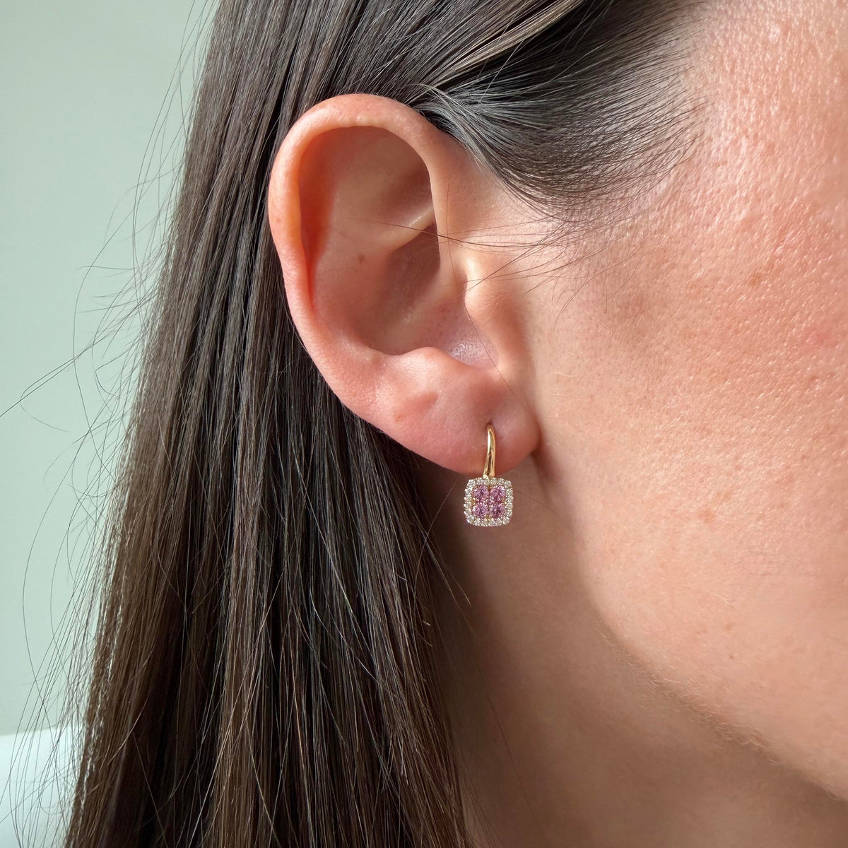 Pink sapphire and diamond cushion cluster earring in 14K yellow gold worn on the ear, showing its size and short drop.