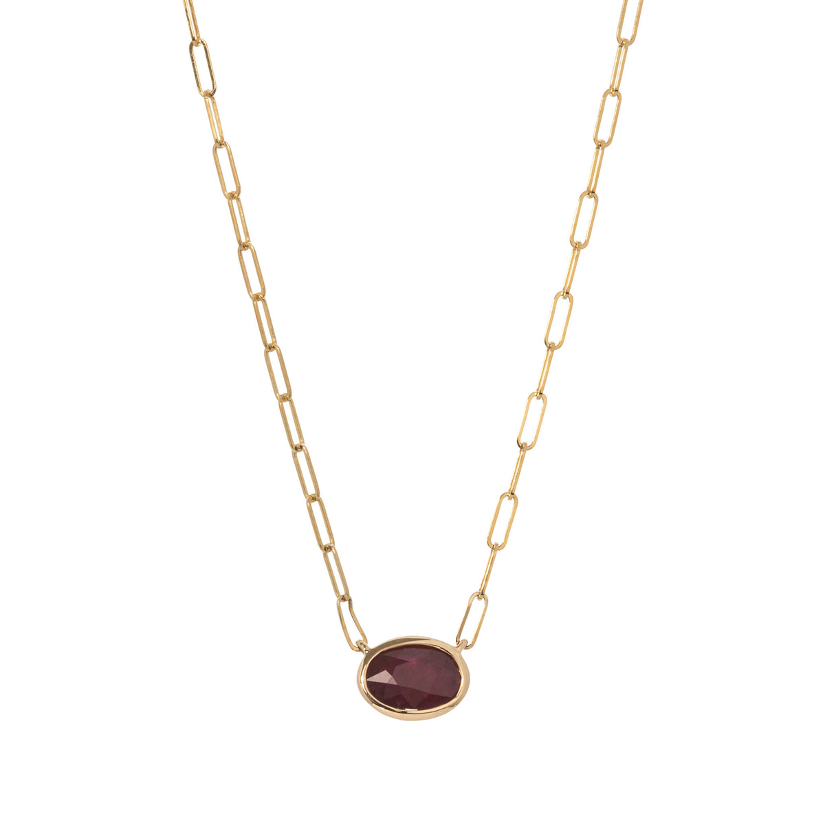Oval ruby bezel-set east-west on a 14K yellow gold paperclip chain, shown on a white background.
