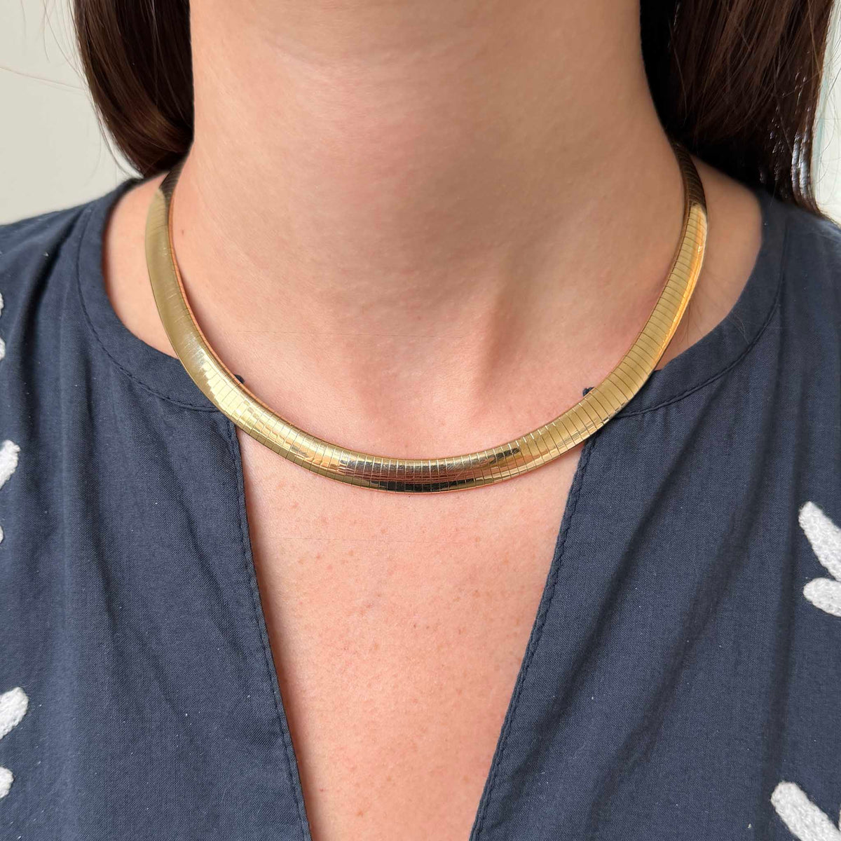 Estate 14K yellow gold Omega collar necklace worn at the collarbone, showing its curved profile and 8 mm width.

