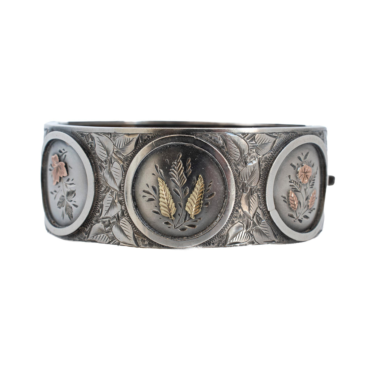Victorian sterling silver wide bangle with gold overlay floral vignettes and engraved leaf detailing.