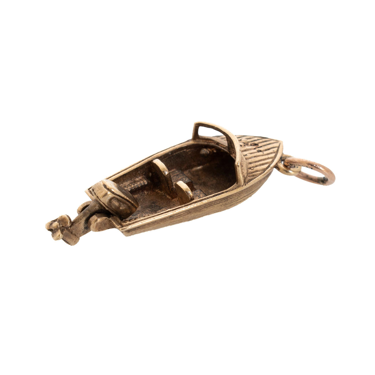 Angled view of a vintage 9K yellow gold motorboat charm with an open cockpit, two seats, and an outboard motor.