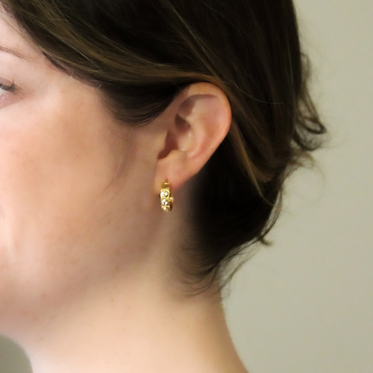Elizabeth Locke diamond and hammered yellow gold hoop earring worn on the ear, showing its size and fit.