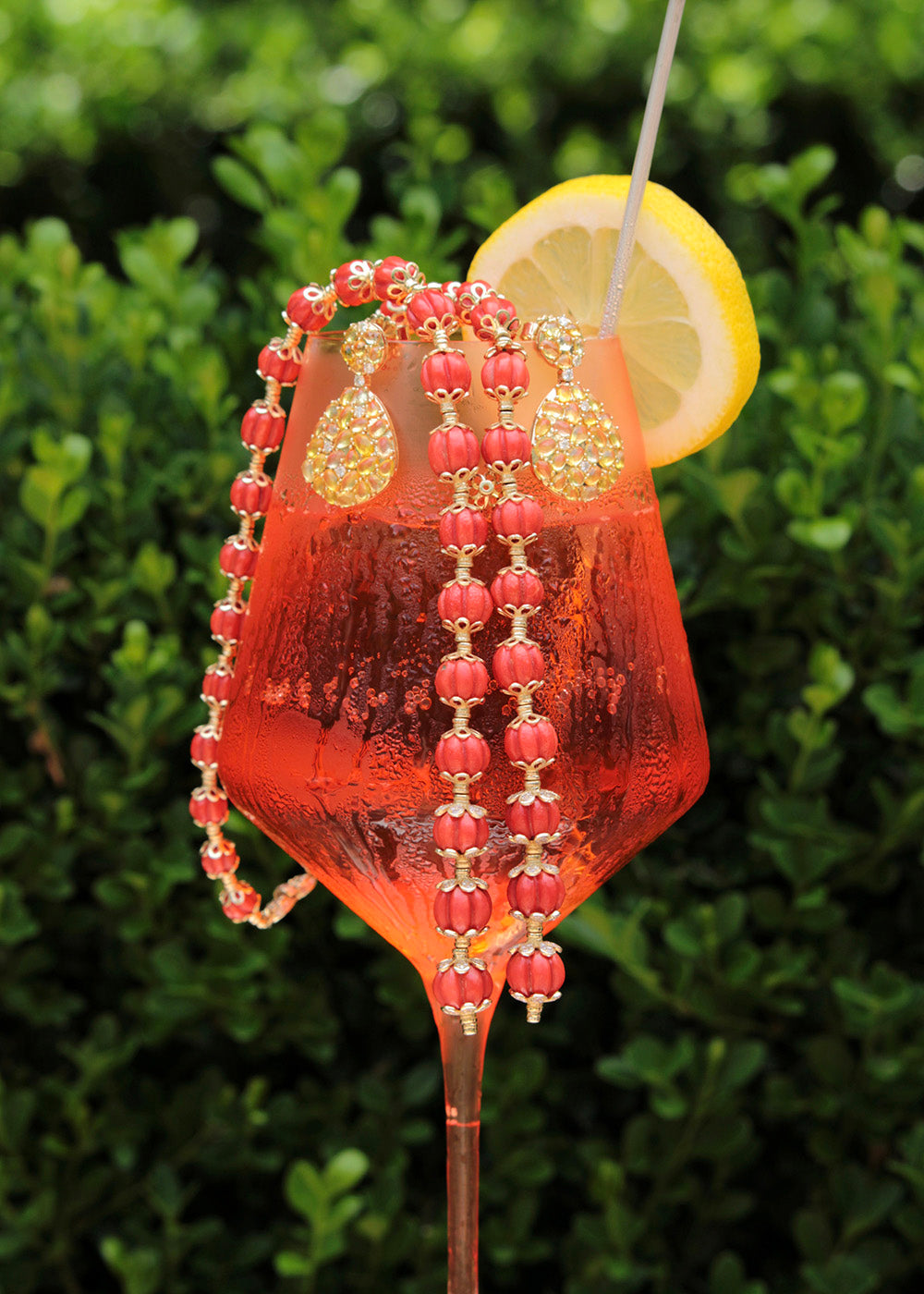 Coral necklace and gemstone statement earrings styled with an Aperol Spritz,in warm light from Croghan's Jewel Box, Charleston SC